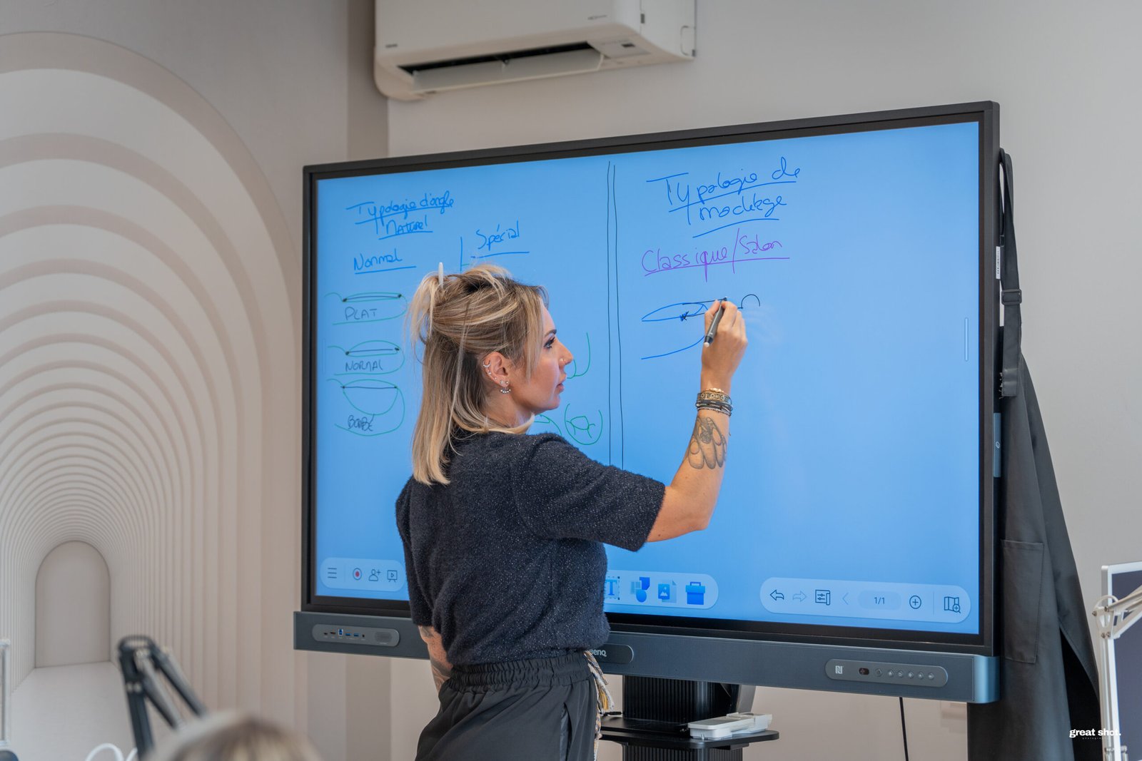 Une formatrice au métier de prothésiste ongulaire en train d'écrire du texte sur un tableau interactif